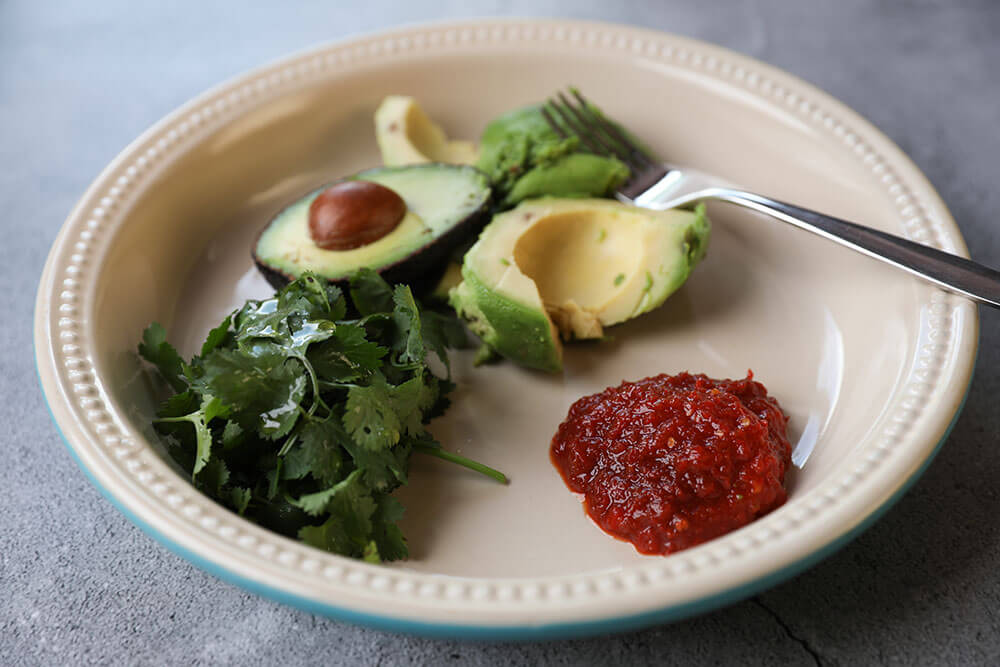 TIGER LILY PEPPER® & LIME SAMBAL GUACAMOLE with avocado on a plate